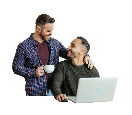 Couple smiling at one another with a laptop and a cup of coffee